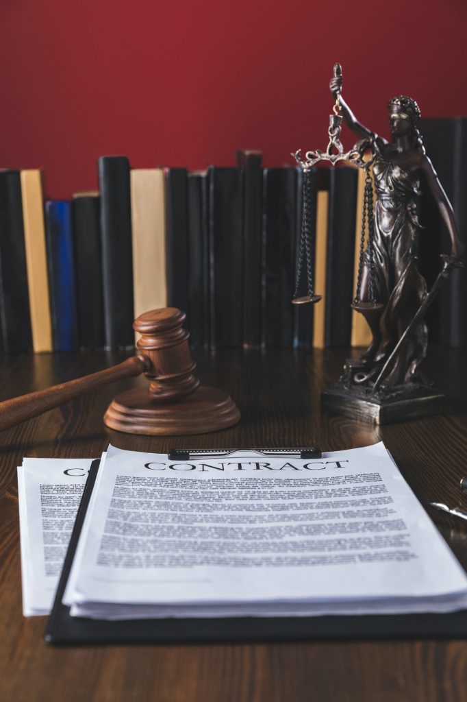 juridical contract on wooden table with hammer and lady justice, law concept